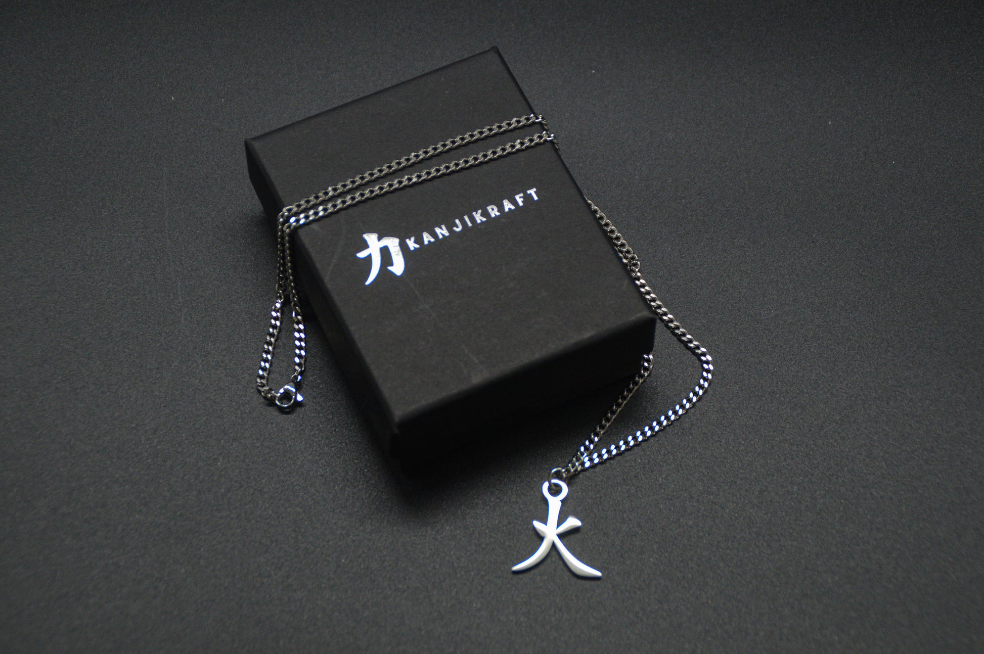 Feuer Kanji Halskette aus der Godai Kollektion. Minimalistischer Japan Schmuck mit dem (火) Hi-Schriftzeichen als Edelstahl Anhänger auf einer edlen KanjiKraft Geschenkbox.