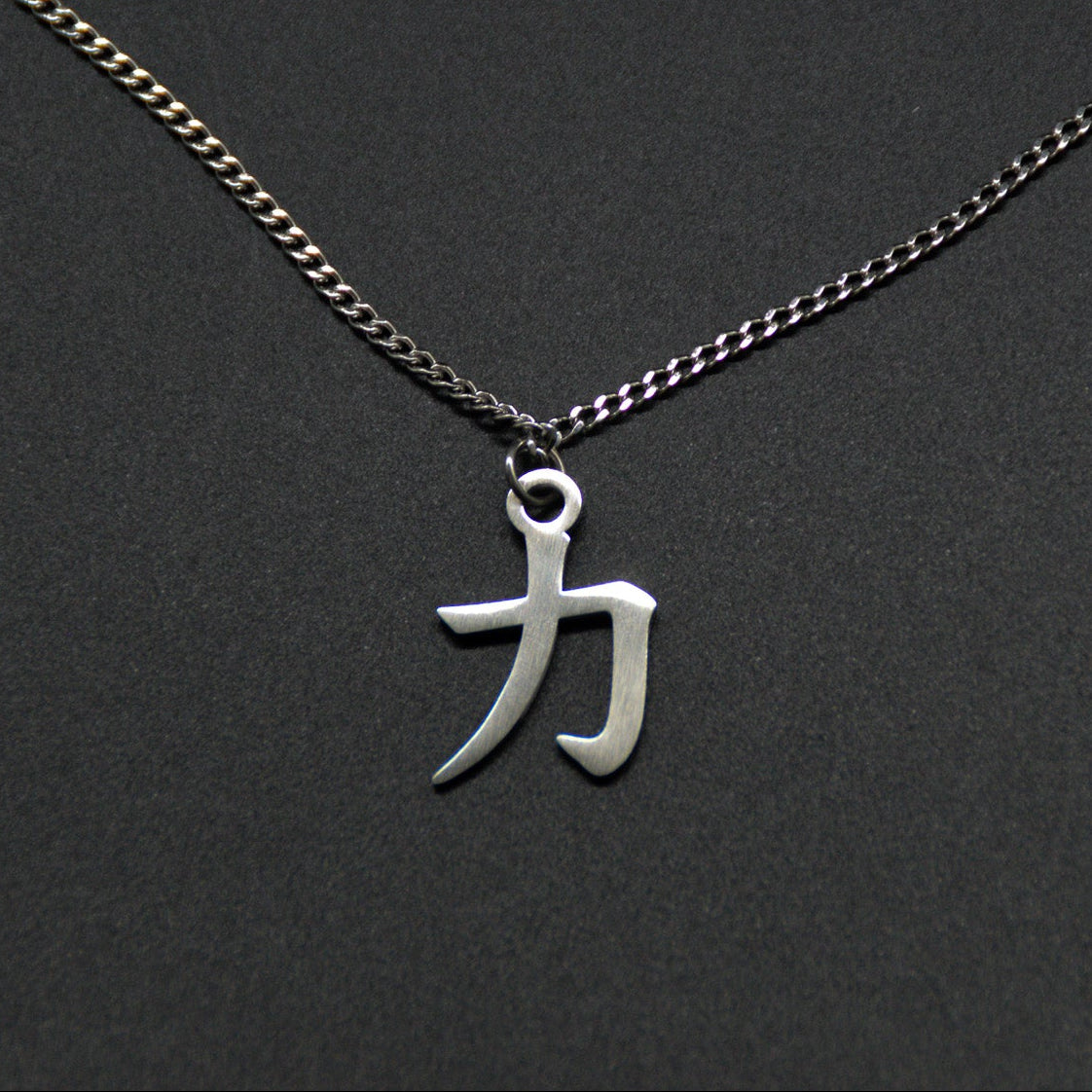 Das Japanische Schriftzeichen für Kraft als Edelstahlkette auf einem Schwarzen Hintergrund. Das gleiche Kanji wie im Logo von KanjiKraft.