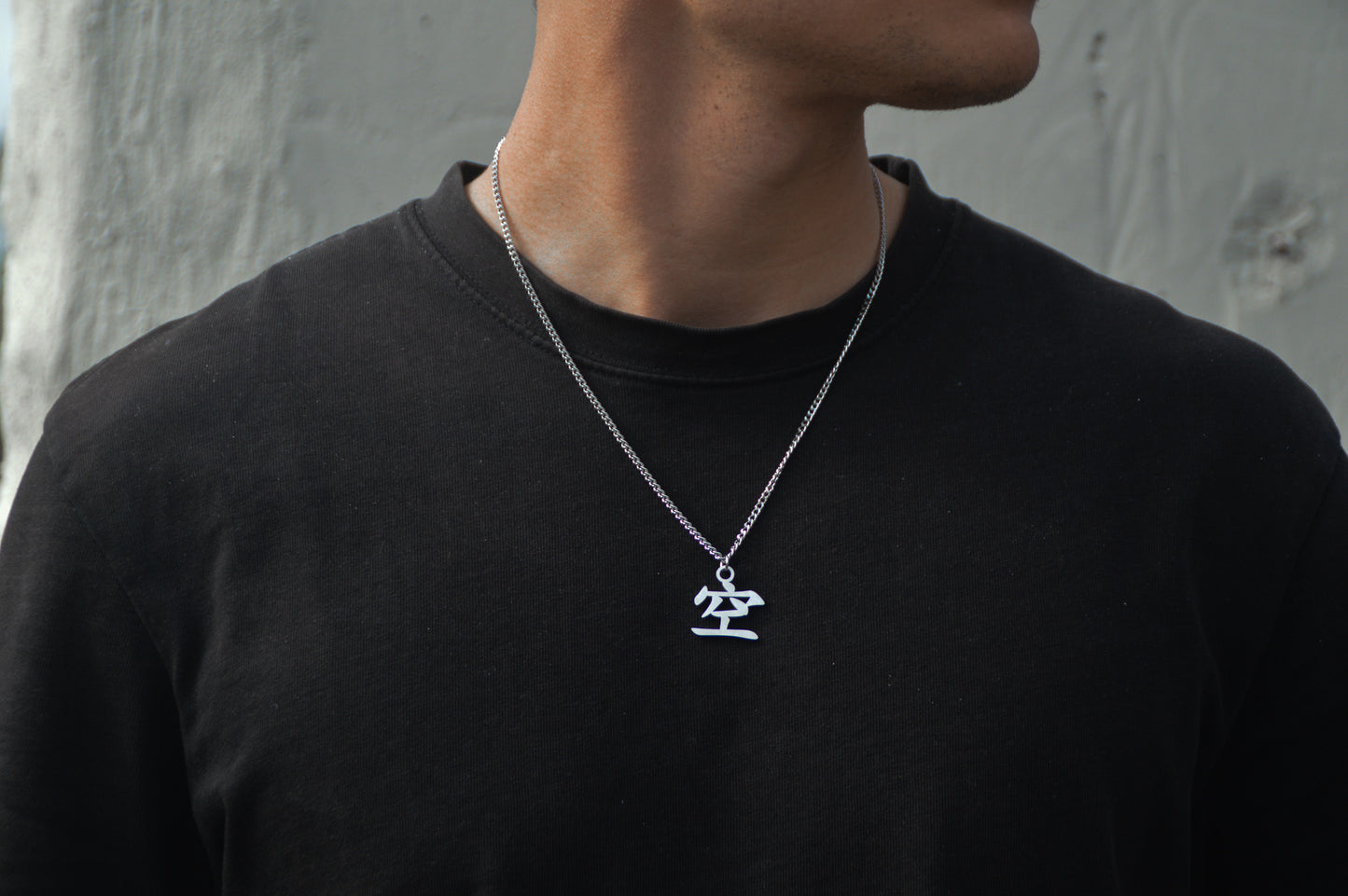 (空) Leere Kanji Halskette aus der Godai Kollektion. Frontales Model Foto, mit schwarzem Tshirt und Blick zur Seite.