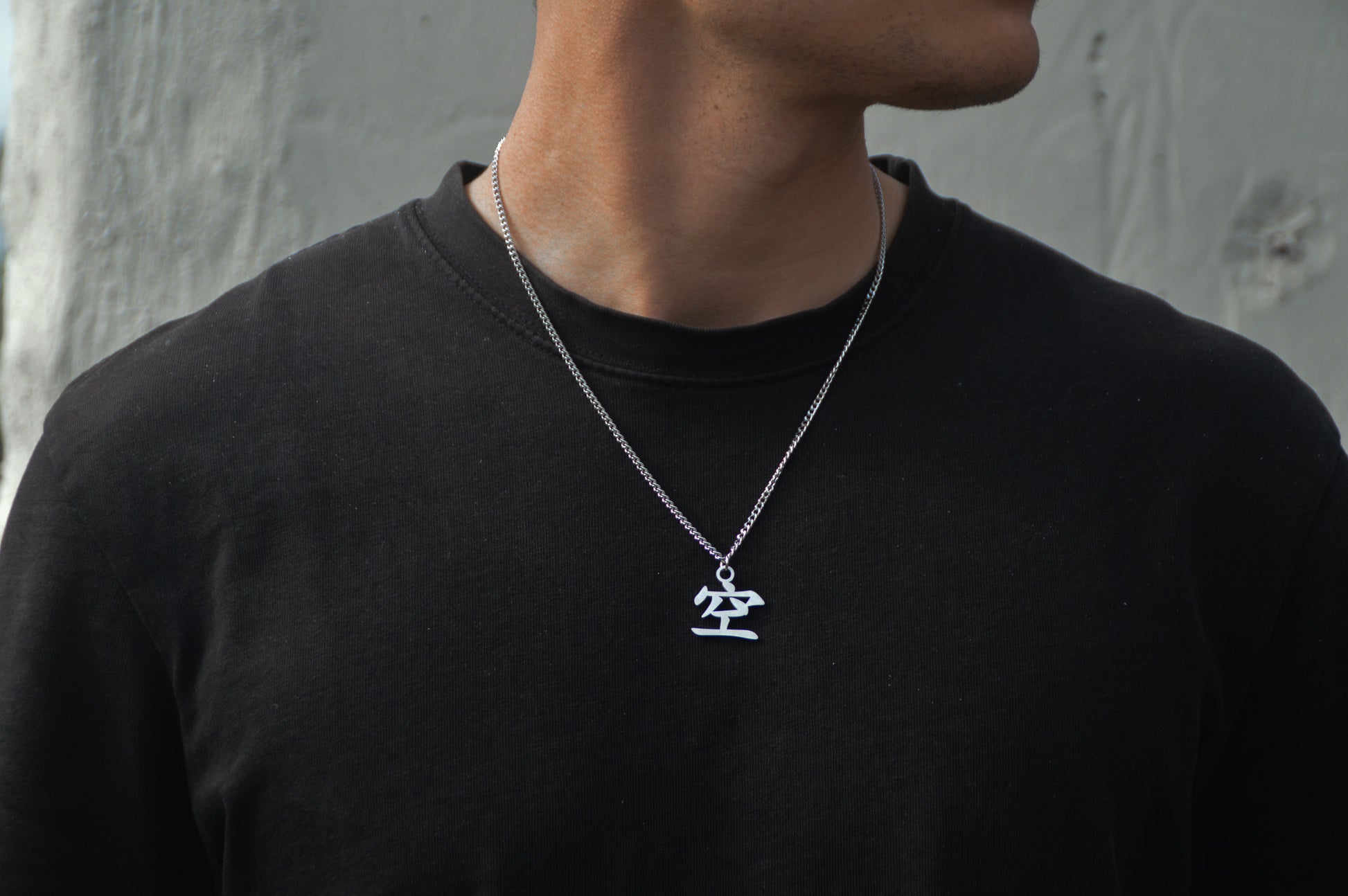 (空) Leere Kanji Halskette aus der Godai Kollektion. Frontales Model Foto, mit schwarzem Tshirt und Blick zur Seite.