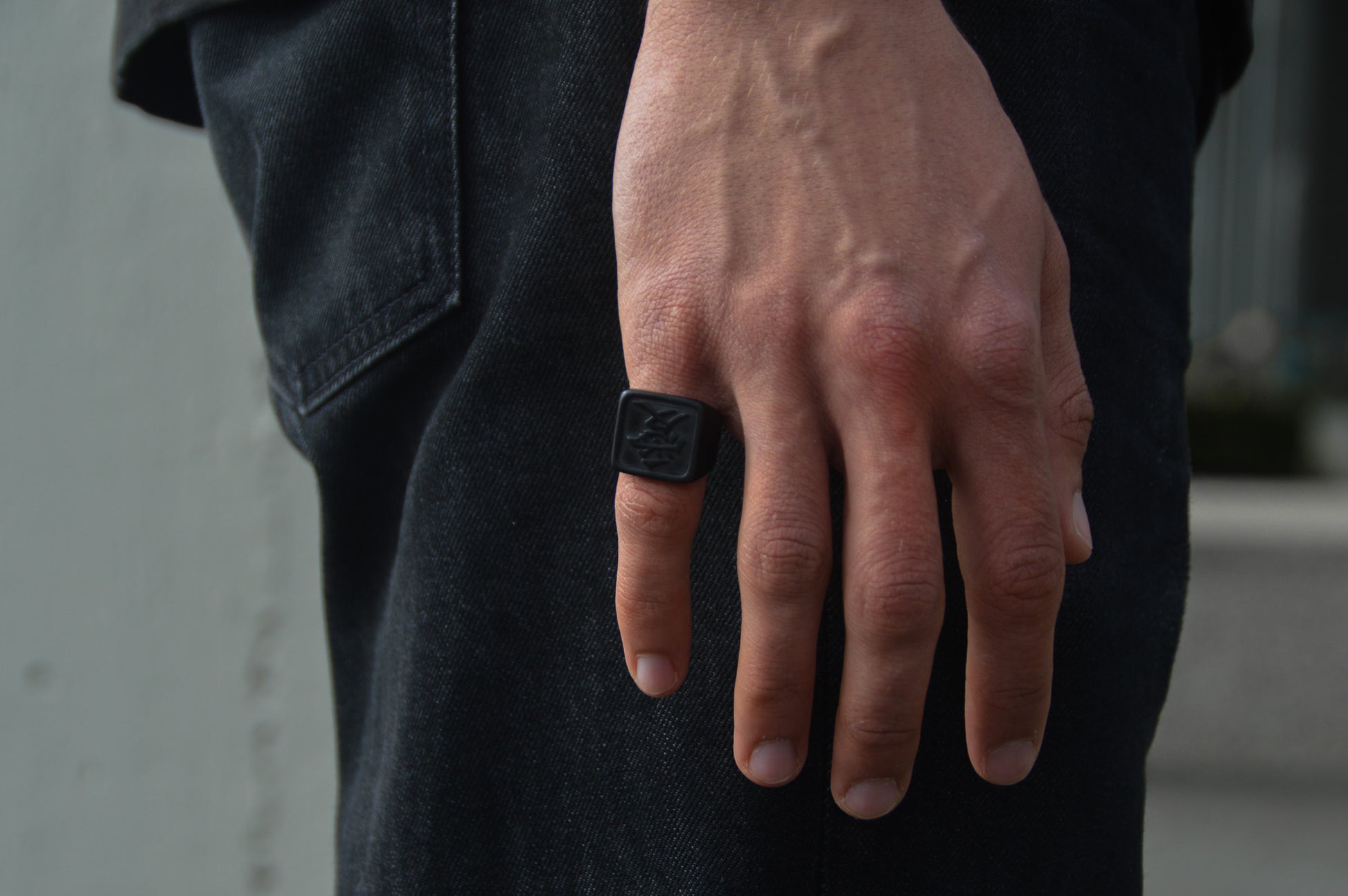 Das Japanische Schriftzeichen für Liebe auf einem Ring. Der Ring ist optisch ein Stempel Ring / Stamp Ring, wobei das Kanji 愛 drauf ist. Zu sehen ist der Schwarze Ring getragen an einer Hand auf dem kleinen Finger. 