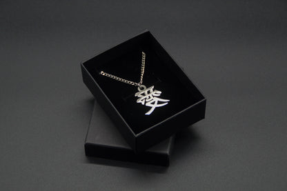 Das Japanische Schriftzeichen (Kanji für Liebe). Edelstahl Halskette mit dem Schriftzeichen 愛 als Anhänger auf einem Schwarzen Hintergrund in einer KanjiKraft Geschenkbox verpackt.
