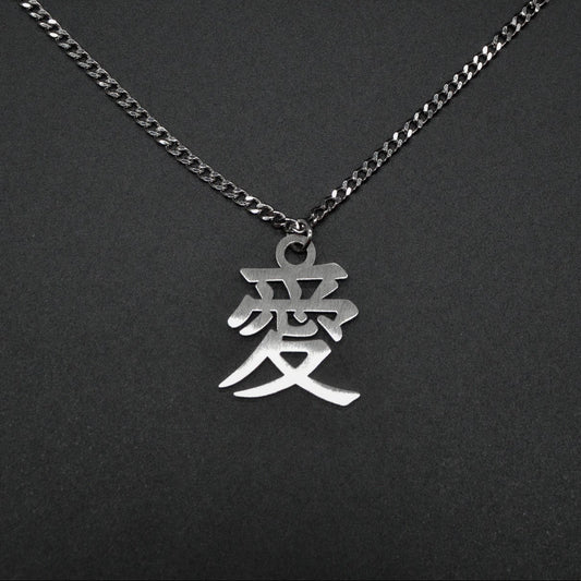 Das Japanische Schriftzeichen (Kanji für Liebe). Edelstahl Halskette mit dem Schriftzeichen 愛 als Anhänger auf einem Schwarzen Hintergrund als Nahaufnahme.