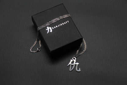 Das Japanische Schriftzeichen für Rache als Edelstahlkette auf einem Schwarzen Hintergrund auf einer KanjiKraft Box liegend