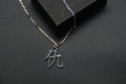 Das Japanische Schriftzeichen für Rache als Edelstahlkette auf einem Schwarzen Hintergrund. Die Kette liegt leicht an einer Kante an.