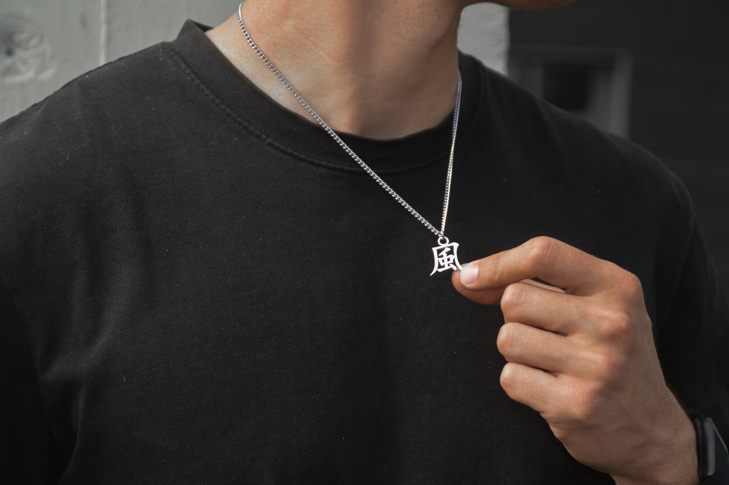 (風) Wind Kanji Halskette aus der Godai Kollektion. Getragen von unseren Model und in die Kamera gehalten. Es sitzt perfekt und sieht cool aus.